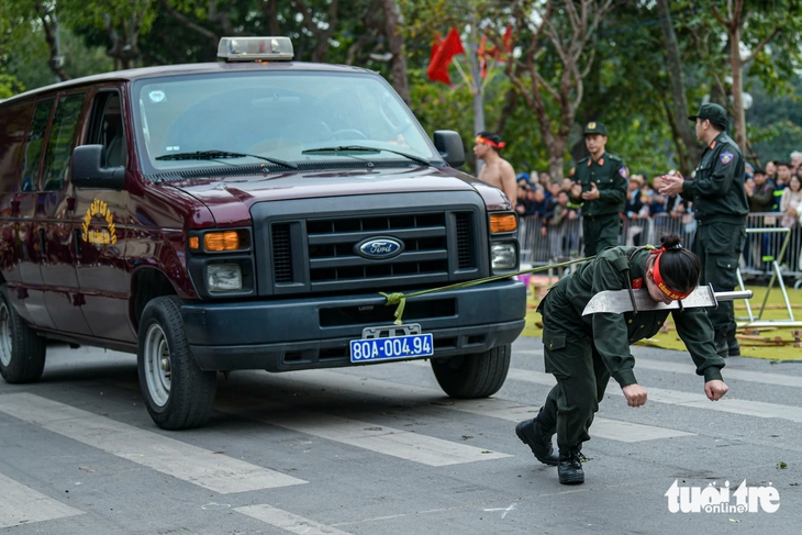 A female public security officer demonstrates incredible strength by pulling a car with a rope while pressing a sword against her neck at a rehearsal in Hanoi, Vietnam, March 7, 2025. Photo: Nam Tran / Tuoi Tre