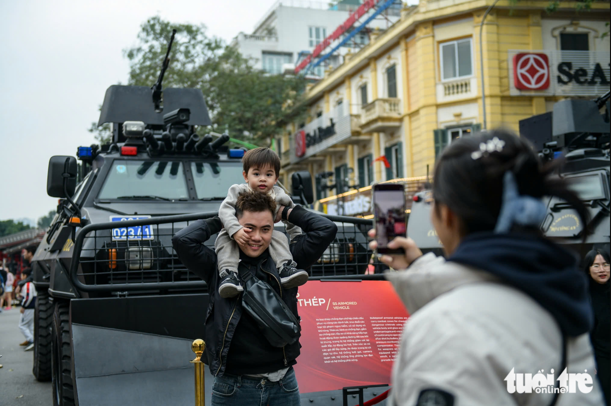 Residents pose for a photo with an armored vehicle in the Ho Guom pedestrian area, Hanoi.