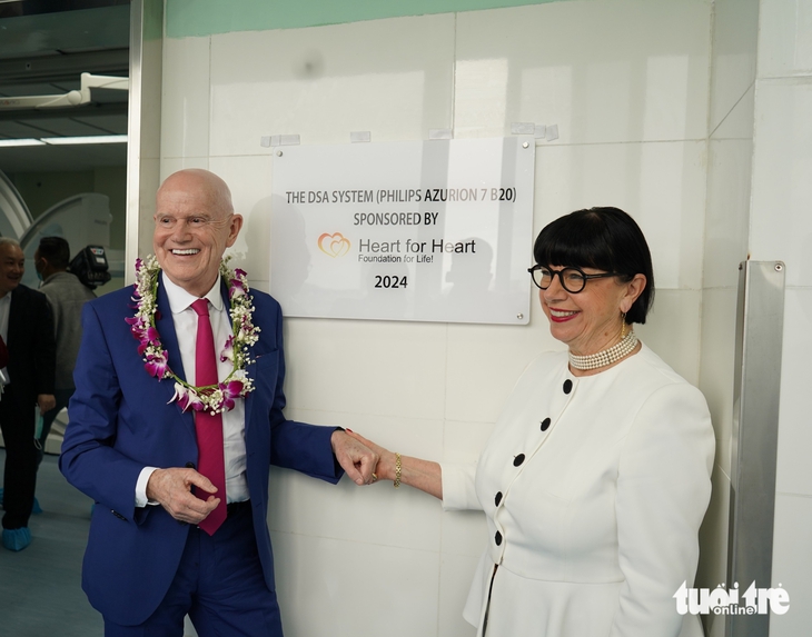 German Prof. Dr. Erich Johann Lejeune and his wife pose in front of a sign featuring the DSA system funded by the ‘Heart for Heart – Foundation for Life!' at Da Nang Hospital in Da Nang City, central Vietnam, March 18, 2025. Photo: Doan Nhan / Tuoi Tre