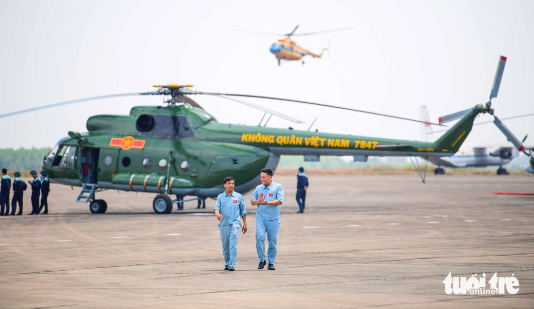 Two helicopter pilots discuss technical issues during a rehearsal at Bien Hoa Airbase in Dong Nai Province, southern Vietnam, in preparation for their participation in a military parade scheduled for April 30, 2025 in Ho Chi Minh City to honor Vietnam’s Reunification Day. Photo: Quang Dinh / Tuoi Tre