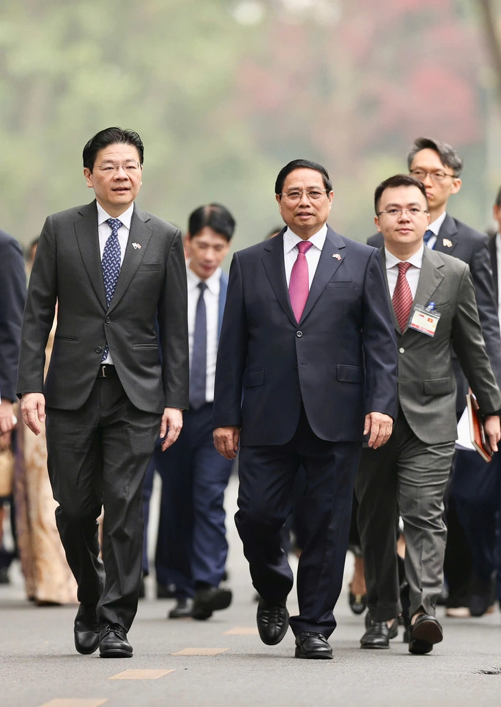 Vietnamese Prime Minister Pham Minh Chinh and his Singaporean counterpart, Lawrence Wong (L), walk toward the Government Office in Hanoi, March 26, 2025. Photo: Nguyen Khanh / Tuoi Tre