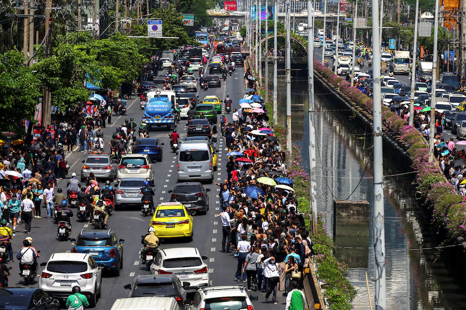 People stand on the road as cars drive through the traffic after a strong earthquake struck central Myanmar on Friday, earthquake monitoring services said, which affected Bangkok as well with hundreds of people pouring out of buildings in the Thai capital in panic after the tremors, in Bangkok, Thailand, March 28, 2025. Photo: Reuters
