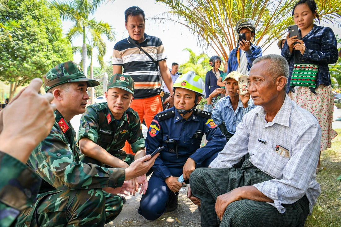 Earthquake victim Htet Maung Maung’s father (R, 1st) shares information about his son with a Vietnamese sapper (L, 1st) and other rescuers after Maung was rescued, April 2, 2025. Photo: Thanh Dat / Tuoi Tre
