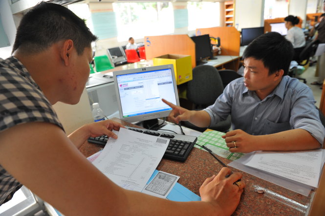 Cán bộ Cục Thuế TP.HCM hướng dẫn người dân làm thủ tục qua mạng. Ngành thuế triển khai  rầm rộ thủ tục thuế qua mạng nhằm đẩy nhanh hiệu quả công việc và giảm bớt tiếp xúc giữa  cán bộ thuế và người nộp thuế  - Ảnh: Thanh Đạm
