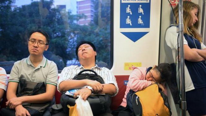 Nhiều người tranh thủ ngủ khi đang đi trên tàu điện - Ảnh: Straits Times