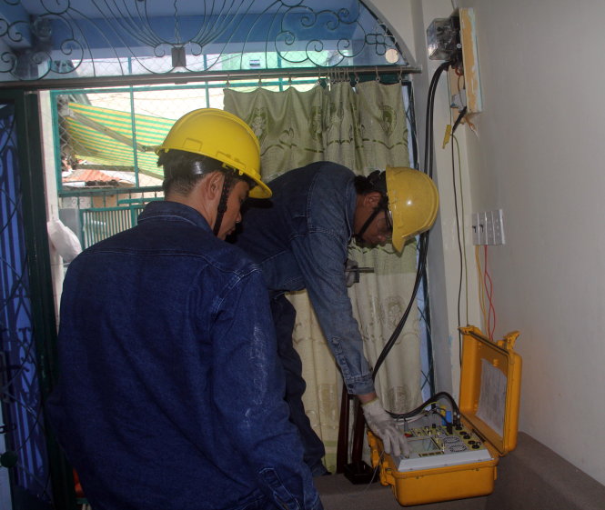 Nhân viên Công ty điện lực Gia Định kiểm tra đồng hồ điện nhà anh Đinh Anh Tuấn, 137/7 Phan Văn Trị, Q.Bình Thạnh sau khi nhận phản ánh tiền điện tăng. Ảnh Quang Khải chụp ngày 23-6