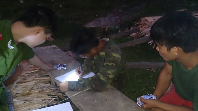 Giữa đêm, công an rọi đèn pin lập biên bản hai lâm tặc bị bắt quả tang đang khai thác gỗ lậu Ảnh: VŨ TOÀN