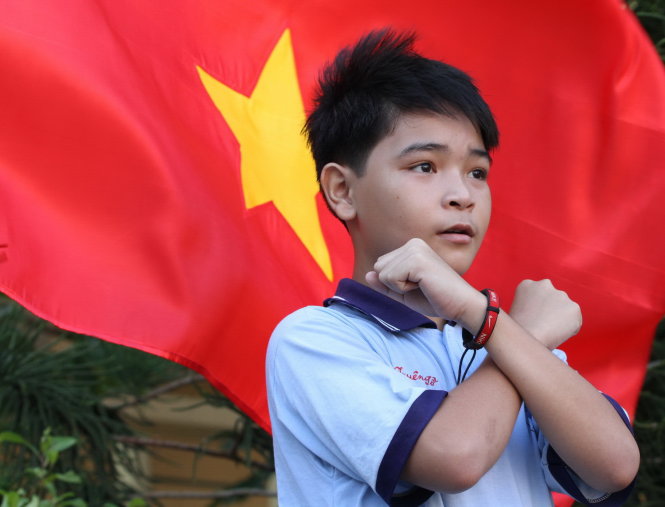 Trong những ngày này, thầy trò Trường khuyết tật Nhân Ái (TP Mỹ Tho, tỉnh Tiền Giang) ráo riết tập hát Quốc ca để chuẩn bị buổi chào cờ kỷ niệm 70 năm Quốc khánh. Trong ảnh: em Tuyên Sở, lớp 4A, vinh dự được chọn điều khiển buổi chào cờ. Học sinh của trường nhìn và làm theo các động tác - ngôn ngữ ký hiệu - bài Quốc ca mà Tuyên Sở thực hiện Ảnh: VÂN TRƯỜNG
