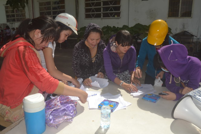 Các công nhân tập trung viết đơn khởi kiện doanh nghiệp vì nợ lương  Ảnh: QUANG PHƯƠNG