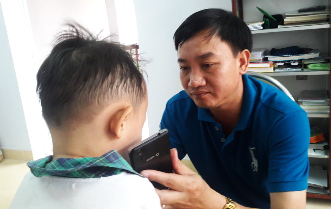Bé Tí nói chuyện với mẹ qua điện thoại của trung tá Vũ Hồng Kiên - Ảnh: Hoàng Điệp