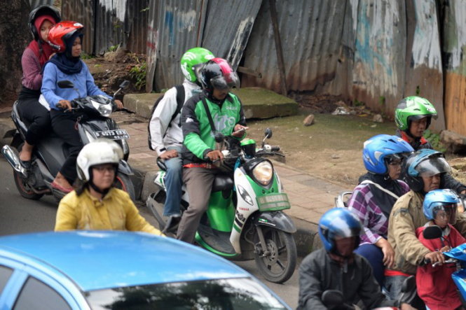 Người lái xe ôm ở Jakarta kiểm tra điện thoại khi chở khách - Ảnh: AFP