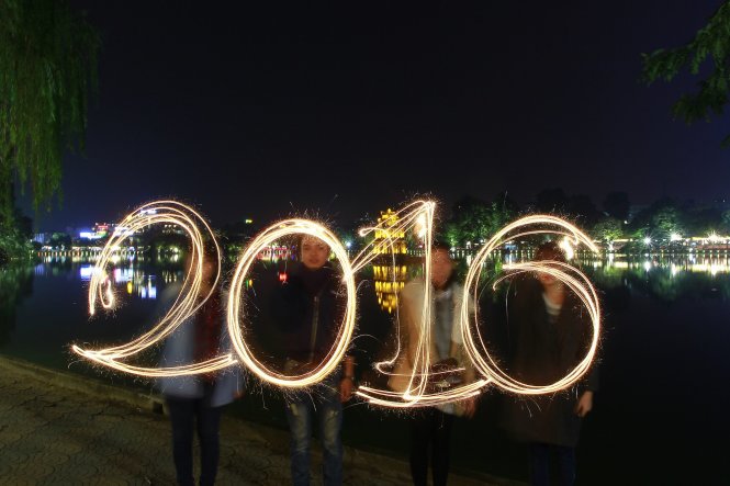 Các bạn trẻ vẽ số 2016 bằng pháo bông bên hồ Hoàn Kiếm - Ảnh: Nam Trần
