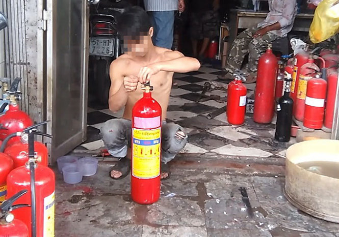 Nhân viên cơ sở chữa cháy M.T trên đường 3 Tháng 2, Q.11, TP.HCM tân trang bình chữa cháy cũ cho khách hàng   Ảnh: ĐỨC PHÚ