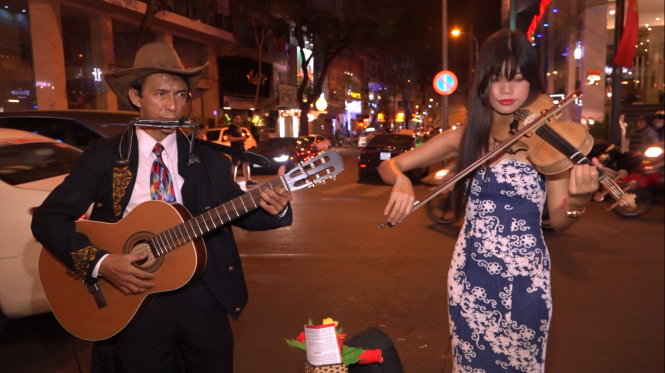 Hòa tấu guitar - vĩ cầm ca khúc Diễm xưa của nhóm anh Nguyễn Hòa Minh, quê Tiền Giang. Anh thường biểu diễn ở vỉa hè phố Tây Bùi Viện  - Ảnh: Chế Thân