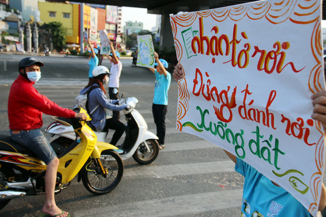 Các sinh viên Trường ĐH Giao thông vận tải chuyển tải thông điệp bảo vệ môi trường tại ngã tư Hàng Xanh - Ảnh: Ngọc Hiển