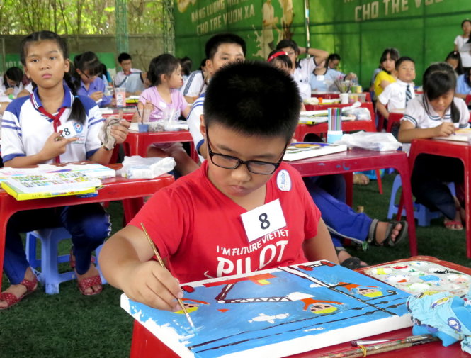 Em Dương Ngọc Bảo Long - lớp 1 trường Nguyễn Thái Sơn, Q.3 và bức tranh Em yêu chú thợ điện đang vẽ trên vải bố. Ảnh: L.Điền
