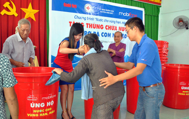 Đại diện các hộ dân lên sân khấu nhận thùng chứa nước - Ảnh: K.Nam.