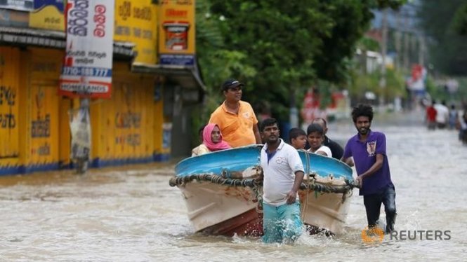 Dân làng dùng thuyền cứu người trên một con đường tại Biyagama - Ảnh: Reuters