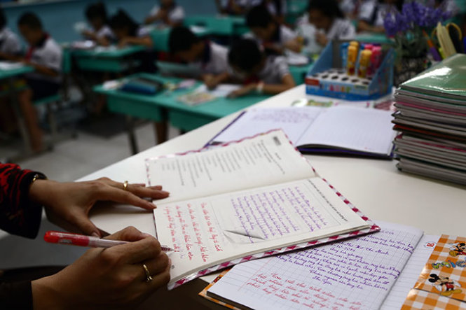 Giáo viên một trường tiểu học tại TP.HCM viết nhận xét cho học sinh theo thông tư 30 - Ảnh: Như Hùng