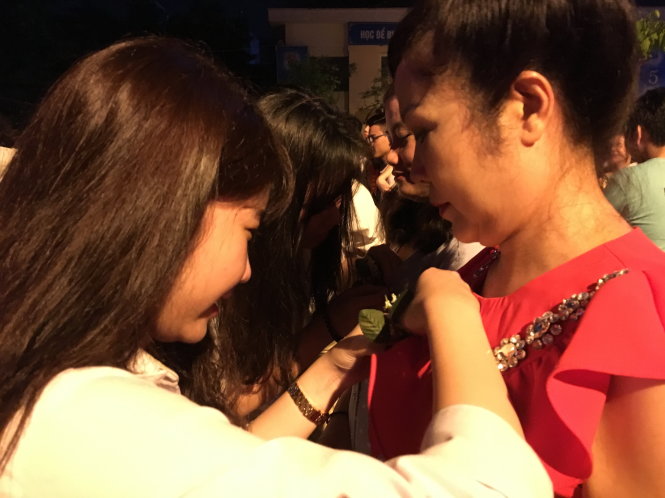 Một học sinh cài hoa lên ngực mẹ trong lễ tri ân-VĨNH HÀ