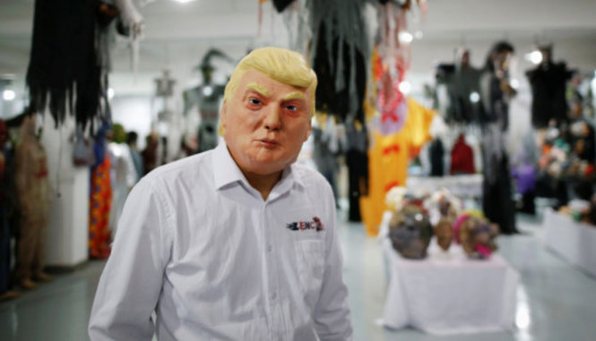 Một người đeo mặt nạ tỉ phú Donald Trump - Ảnh: REUTERS