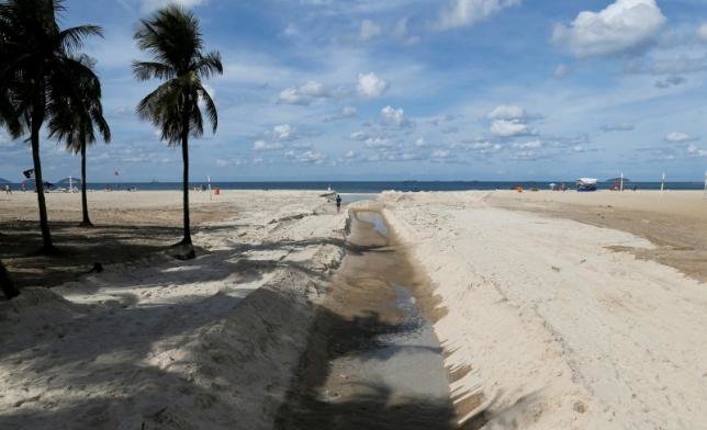 Một người đàn ông đang chạy bên mương nước thải tại bãi biển Copacabana ở Rio de Janeiro, Brazil - Ảnh: Reuters