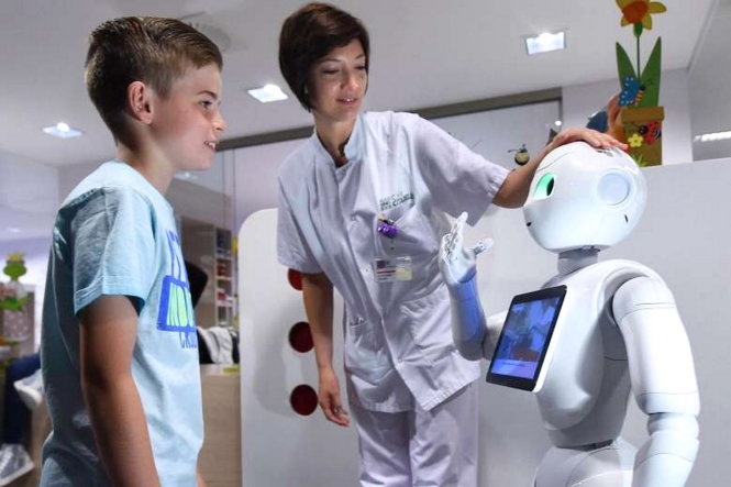 Robot Pepper đang nói chuyện với một cậu bé tại bệnh viện khu vực La Citadelle ở Liege, Bỉ hôm 13-6 - Ảnh: AFP