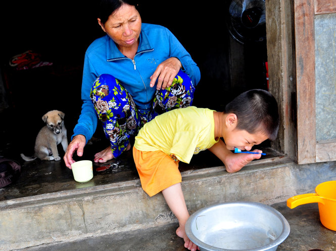 Có bà ngoại ngồi bên cạnh, em vẫn tự lực đánh răng bằng bàn chân yếu ớt của mình