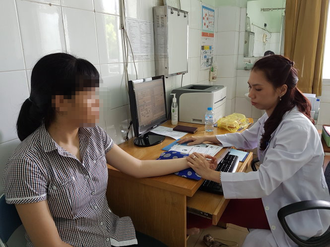 Bác sĩ đang bắt mạch điều trị mụn trứng cá cho bệnh nhân - Ảnh: B.L
