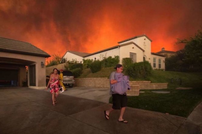 Người dân ở gần Santa Clarita ôm đồ đi sơ tán khi cháy rừng lan rộng - Ảnh: AFP