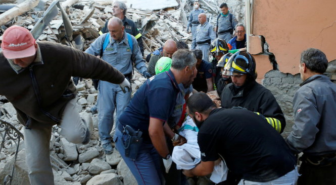 Lực lượng cứu hộ đang khiêng 1 người ra khỏi đống đổ nát ở Amatrice, Ý - Ảnh: REUTERS