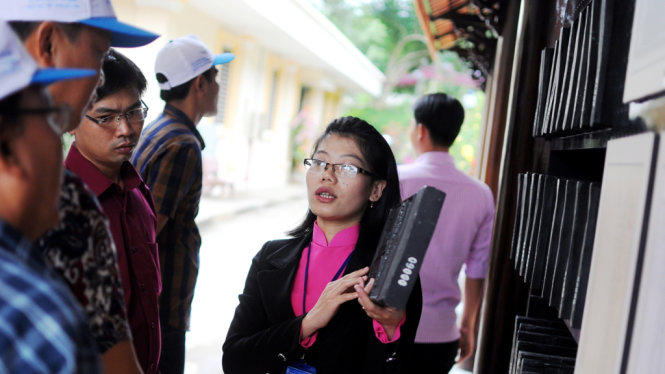 Hướng dẫn viên đang giới thiệu cho khách tham quan về Mộc bản tại buổi triển lãm - Ảnh: Lâm Thiên