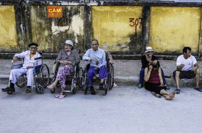 Ba người già ngồi nói chuyện với nhau ở một góc công viên, bên cạnh là những người giúp việc-Nguyễn Khánh