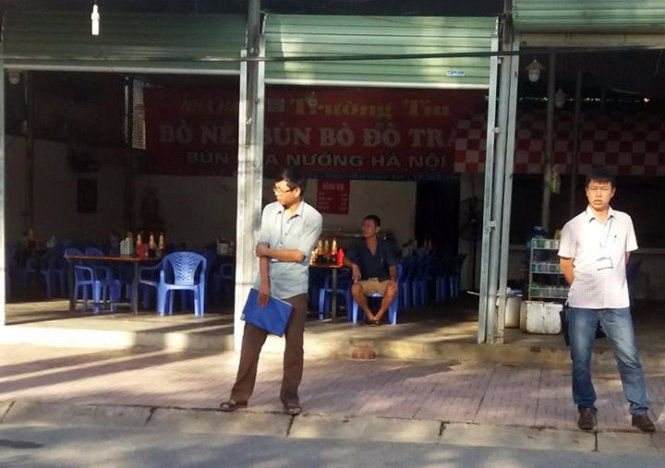 Các cán bộ thuế đứng trước quán 