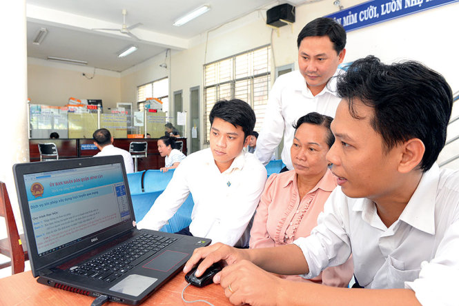 Người dân tìm hiểu cách nộp hồ sơ qua mạng tại UBND Q.Bình Tân sáng 1-10 -Ảnh: HỮU KHOA