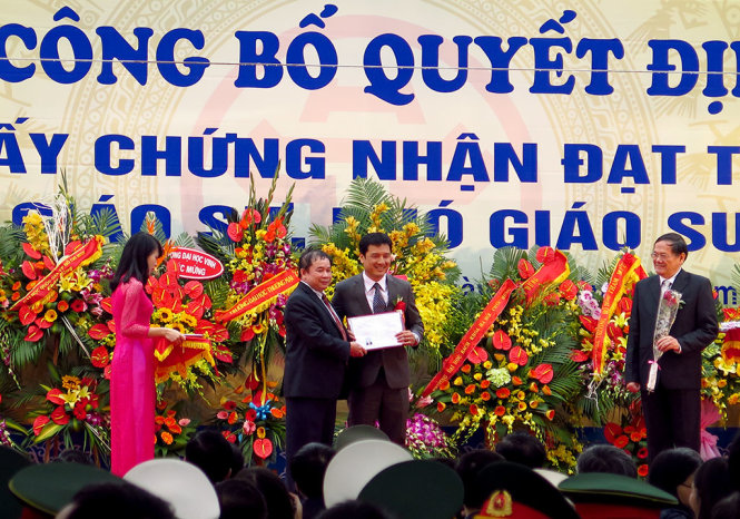 Thứ trưởng Bộ GD-ĐT Bùi Văn Ga - Phó Chủ tịch Hội đồng chức danh giáo sư Nhà nước - trao giấy chứng nhận đạt tiêu chuẩn chức danh PGS cho một tân PGS tại Lễ công bố quyết định và  trao giấy chứng nhận đạt tiêu chuẩn chức danh GS, PGS tháng 2-2015 - Ảnh: NGỌC HÀ