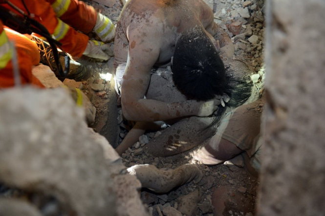 Hình ảnh người cha công nhân dùng thân mình che chắn cho con gái gây xúc động mạnh. Ảnh: AFP