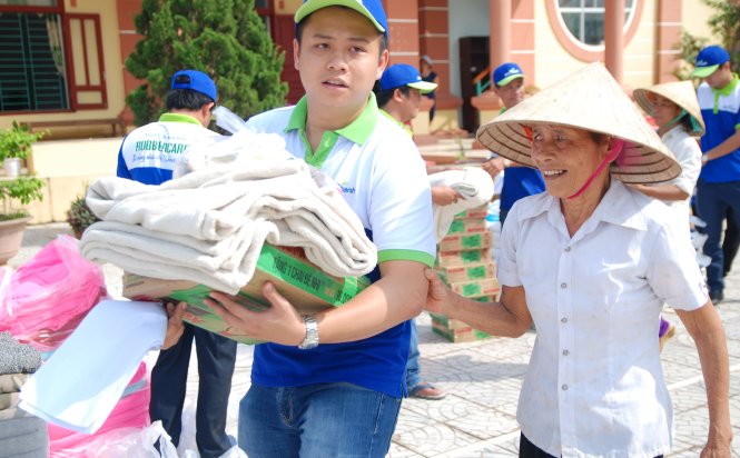 Đại diện công ty TNHH Đức Thành giúp bưng quà cho một người dân vùng lũ xã Mai Thủy, Lệ Thủy, Quảng Bình bị yếu mắt – Ảnh: QUỐC NAM