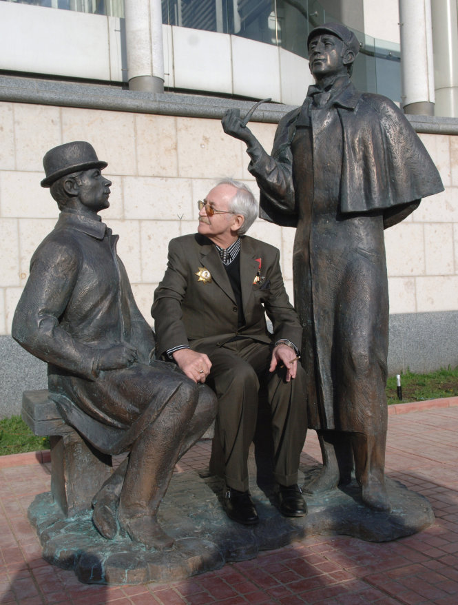 Vasili Livanov trong lễ khánh thành tượng Sherlock Holmes và bác sĩ Watson năm 2007 tại Matxcơva. Vasili Livanov đùa rằng ai ngồi giữa hai người, đặt tay lên quyển sách của bác sĩ Watson sẽ giải quyết được nhiều vấn đề, còn nếu chạm tay vào ống pip của thám tử Sherlock Holmes thì sẽ rơi vào một chuyện hình sự! (tượng của nhà điêu khắc Andrei Orlov)-sputnik-georgia.com