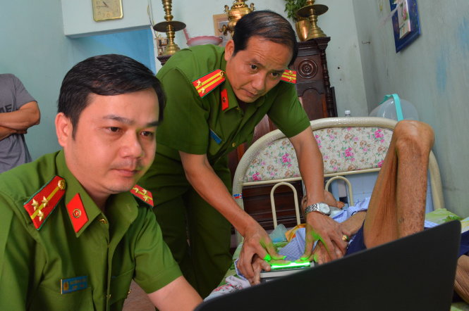 Trung tá Nguyễn Văn Trường (phải) cùng đồng nghiệp đến nhà làm thẻ căn cước cho ông Lương Sỹ
(88 tuổi, Q.12) bị liệt - Ảnh: LĨNH HỒNG