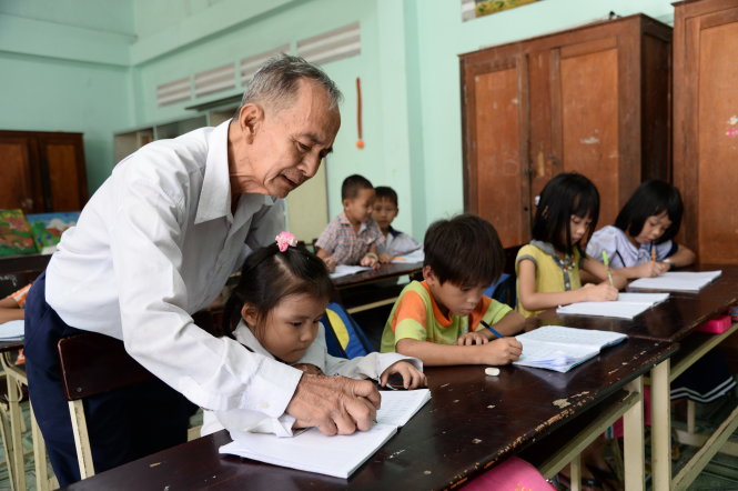Thầy giáo Nguyễn Thanh Hải dạy cho các học sinh lớp 1 nắn nót từng con chữ tại Trung tâm học tập cộng đồng xã Thạnh Lộc, Q.12, TP.HCM - Ảnh: Tự Trung