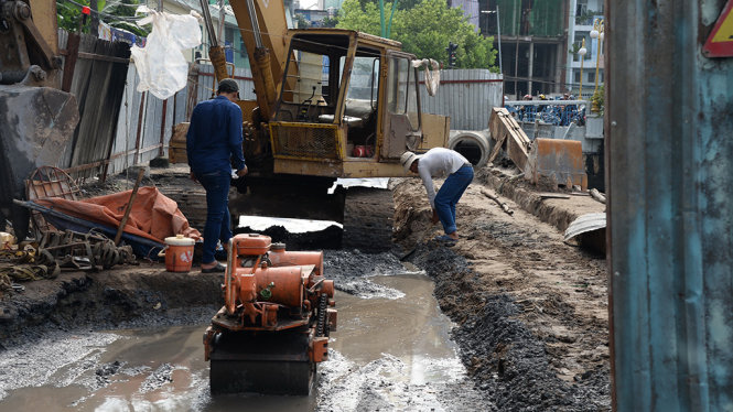 Công nhân đang tiến hành thi công bên trong công trường chuẩn bị tái lập mặt đường - Ảnh: TỰ TRUNG