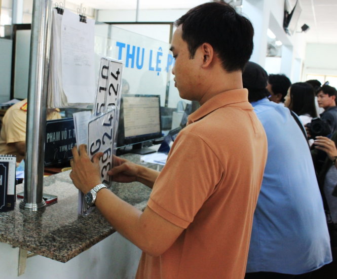 Sau khi làm thủ tục đăng ký qua mạng, anh Lê Minh Trí nhận biển số xe nhanh hơn cách làm trước đây - Ảnh: Sơn Bình