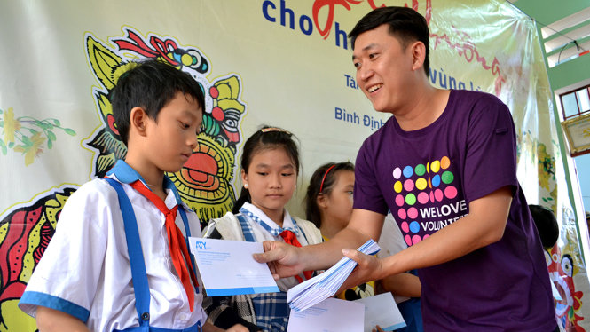Ông Nguyễn Hoàng Minh Tân - giám đốc đối ngoại và marketing Trung tâm Đào tạo tài năng trẻ châu Á – Thái Bình Dương – trao quà cho học sinh vùng lũ P.Bình Định (thị xã An Nhơn) - Ảnh: DUY THANH