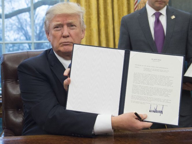 Tổng thống Mỹ Donald Trump cầm tờ sắc lệnh ông vừa ký quyết định rút Mỹ khỏi TPP tại Phòng Bầu dục của Nhà Trắng ở thủ đô Washington, DC ngày 23-1-2017 - Ảnh: AFP