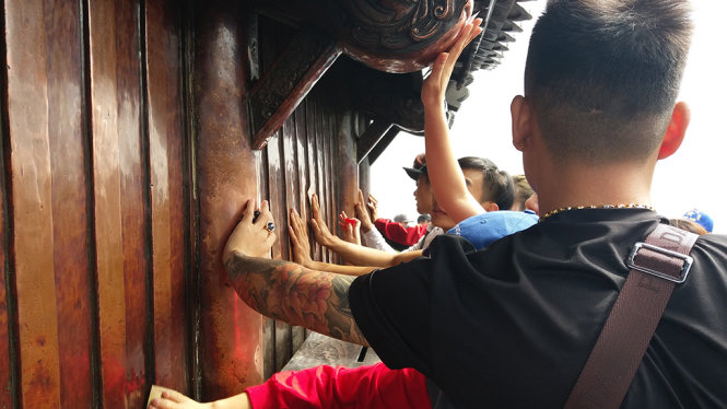 Người lớn và cả trẻ em dùng tiền cọ nhẵn chùa Đồng - Ảnh: ĐỨC HIẾU
