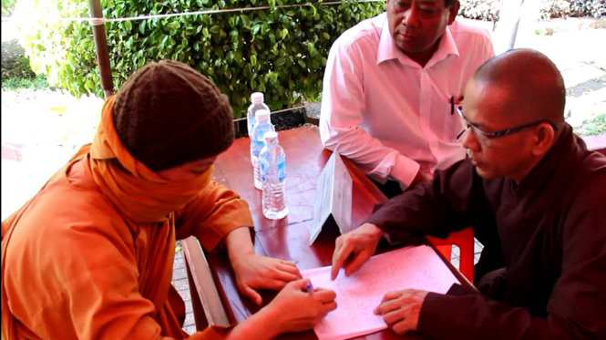 Một sư giả (bên trái, bịt mặt) bị đại diện Ban Trị sự Thành hội Phật giáo Thủ Dầu Một lập biên bản sáng 10-2 - Ảnh: B.Sơn