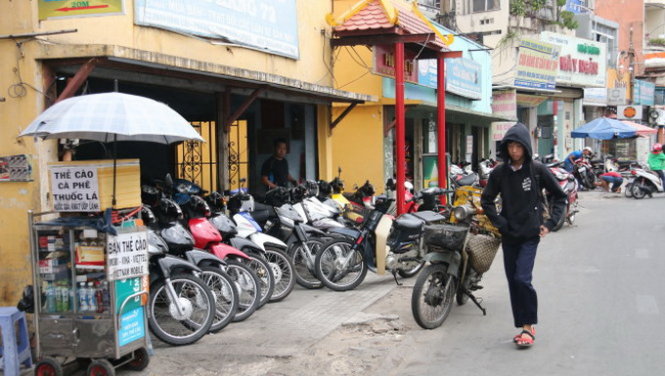 Vỉa hè đường Phan Đăng Lưu (Q.Phú Nhuận) nhỏ hẹp, gạch bong tróc, lại bị chiếm dụng nên người đi bộ phải đi xuống lòng đường - Ảnh: TIẾN LONG