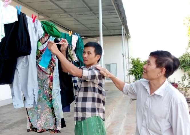 Ông Cường chỉ cho thanh niên cai nghiện trong trại phơi quần áo - Ảnh: THÁI THỊNH