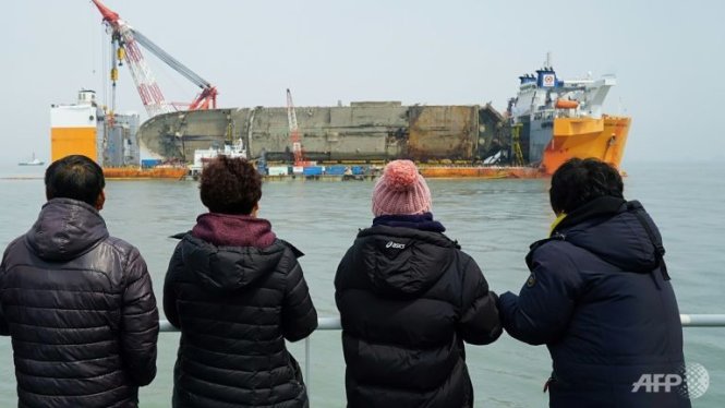 Thân nhân các nạn nhân vẫn còn mất tích trên phà Sewol nhìn xác phà từ xa - Ảnh: AFP